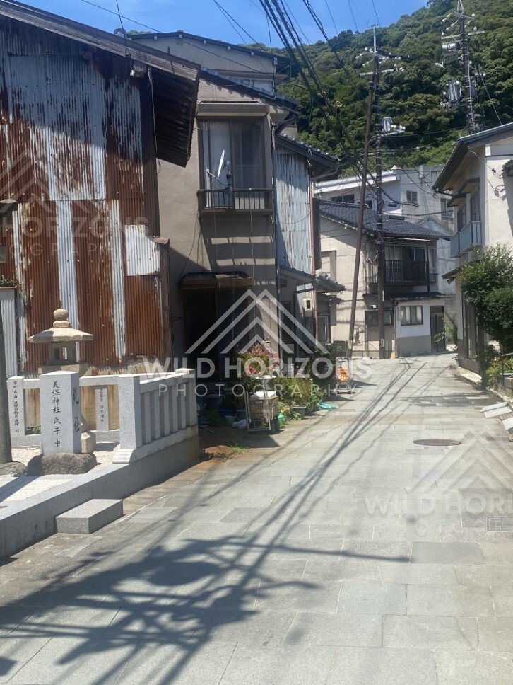 Quiet Street With Corrugated Buildings and Stone Lantern Marker. Mihonoseki, Japan.