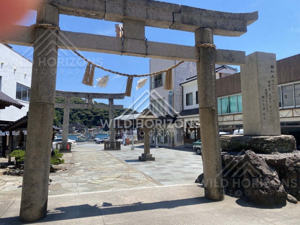 Stone Torii Gate Framing a Harbourfront Street. Mihonoseki, Japan.