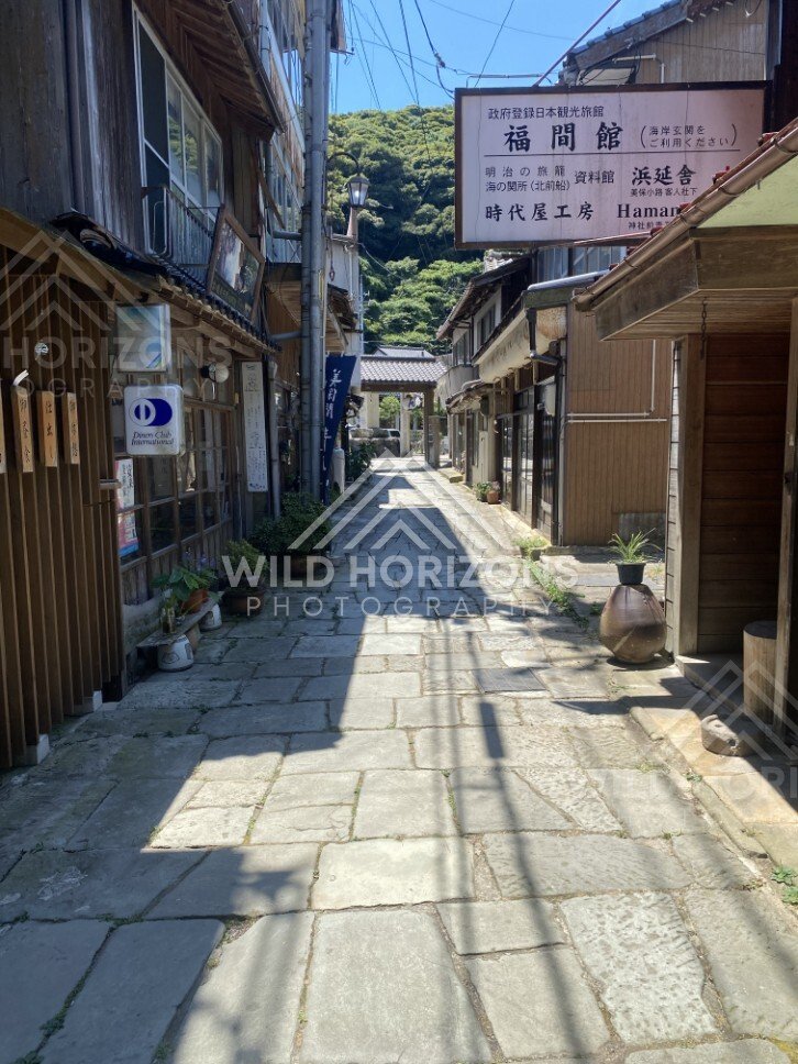 Old Town Street With Japanese Signage and Sunlit Stone Paving. Mihonoseki, Japan.