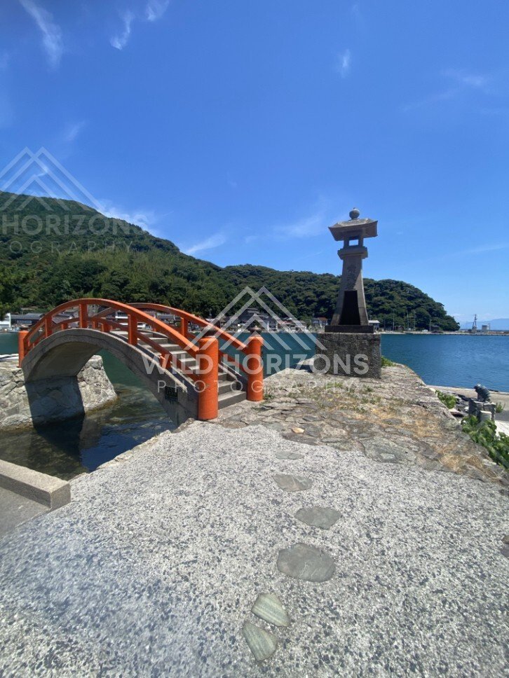Arched Bridge With Red Railings Beside a Stone Lantern on the Pier. Mihonoseki, Japan.
