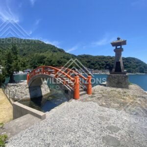 Red arched Bentenjima Bridge beside a stone lantern on the harbour. Mihonoseki, Japan.