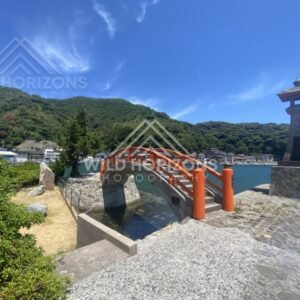 Stone lantern overlooking the red arch of Bentenjima Bridge and the bay. Mihonoseki, Japan.