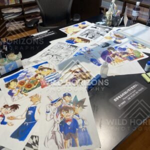 Close-up of artwork sheets on the Gosho Aoyama Manga Factory studio desk exhibit. Hokuei, Japan.