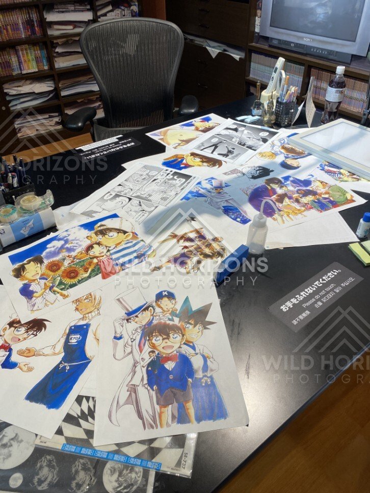 Close-up of artwork sheets on the Gosho Aoyama Manga Factory studio desk exhibit. Hokuei, Japan.