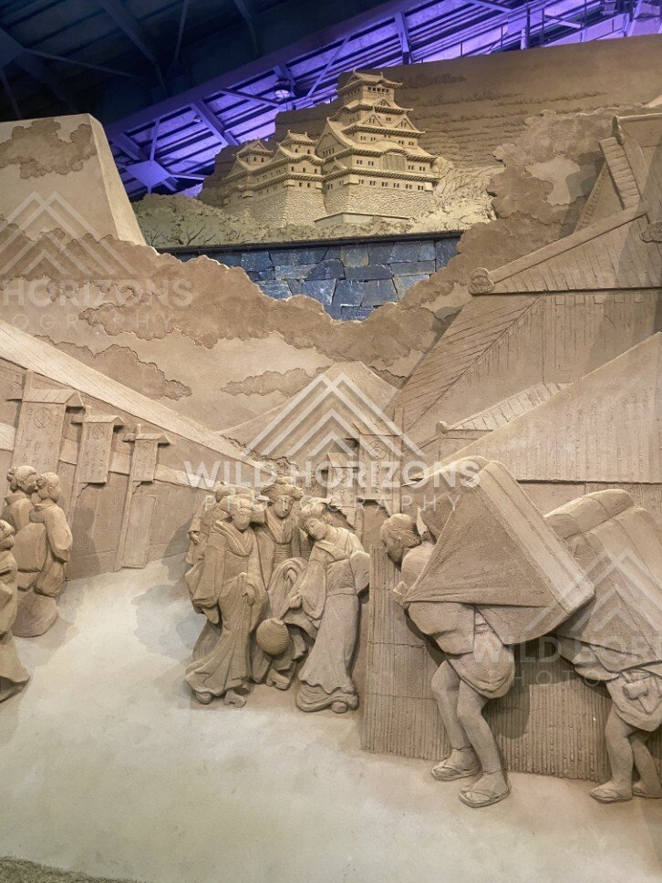 Sand Sculpture Relief of Crowded Scene Along Stone Wall. Tottori Sand Museum, Japan.