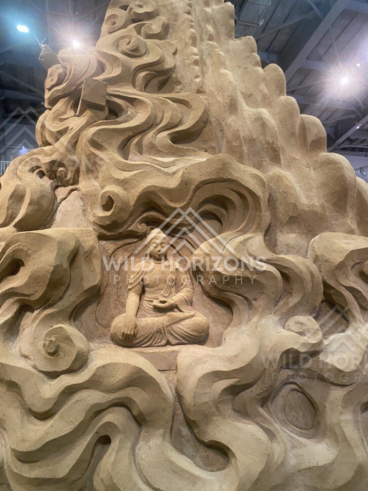 Sand Sculpture of a Buddha Figure Set Within Swirling Clouds. Tottori Sand Museum, Japan