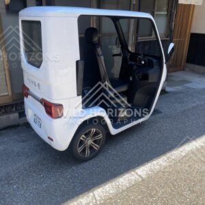 A compact three-wheeled utility vehicle parked on a narrow village street. Ine, Japan