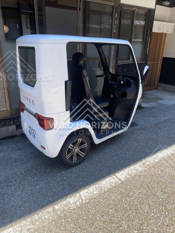 A compact three-wheeled utility vehicle parked on a narrow village street. Ine, Japan