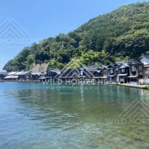 Row of Ine no Funaya boathouses reflected in calm water. Ine, Japan