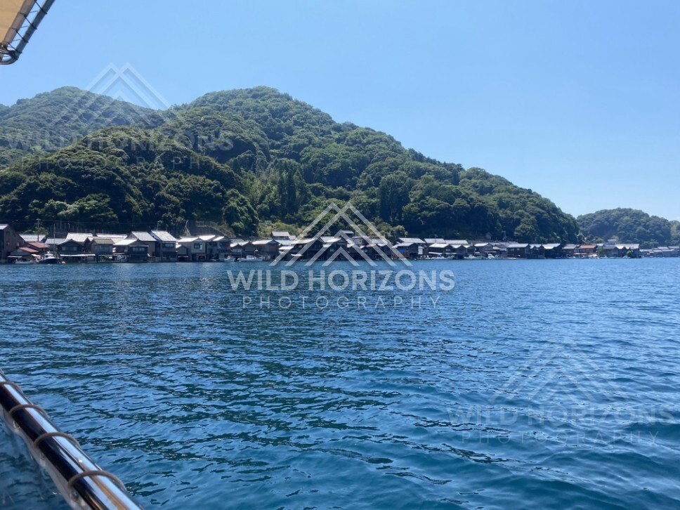 View from a boat toward the coastal village and wooded headlands. Ine, Japan