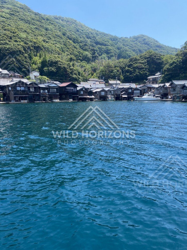 A white motorboat anchored near the funaya boathouses under a clear sky. Ine, Japan