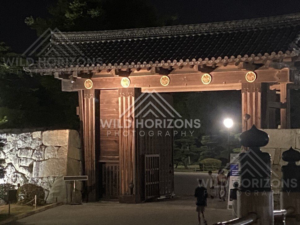 Traditional Wooden Castle Gate Lit Along Stone Walls at Night. Himeji Castle, Japan.
