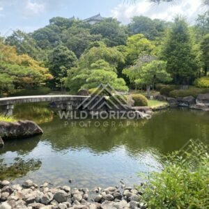 Curved Stone Bridge and Rock Garden Beside a Still Pond. Koko-en Garden, Japan.