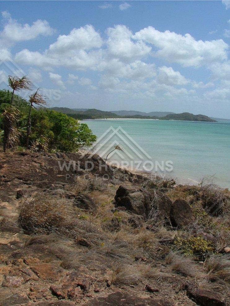 Rocky shoreline viewpoint above calm tropical waters. Seisia, Australia.