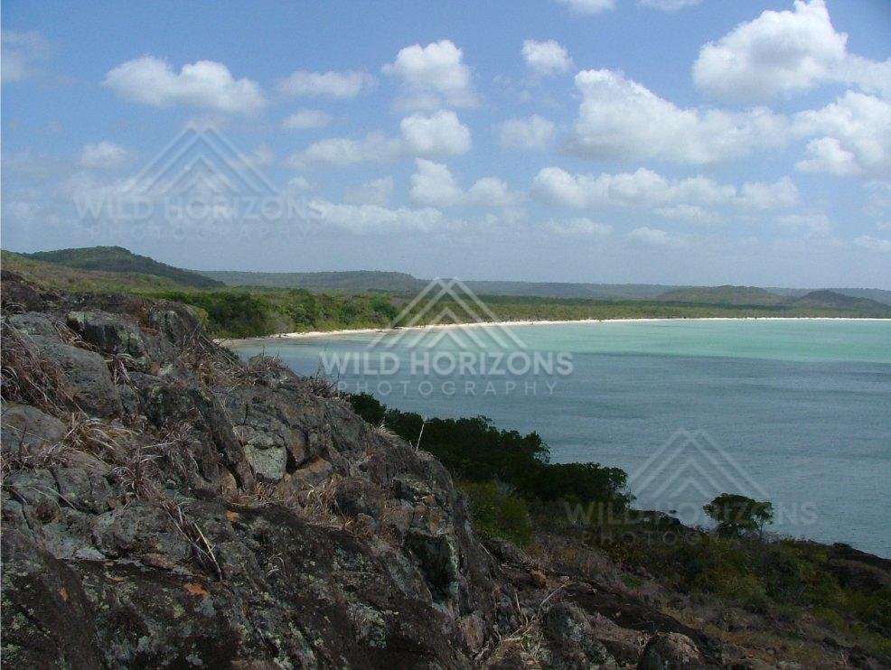 Rocky headland overlooking a broad bay and sandy shoreline. Seisia, Australia.