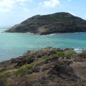 Rugged island headland rising from turquoise coastal waters. Seisia, Australia.