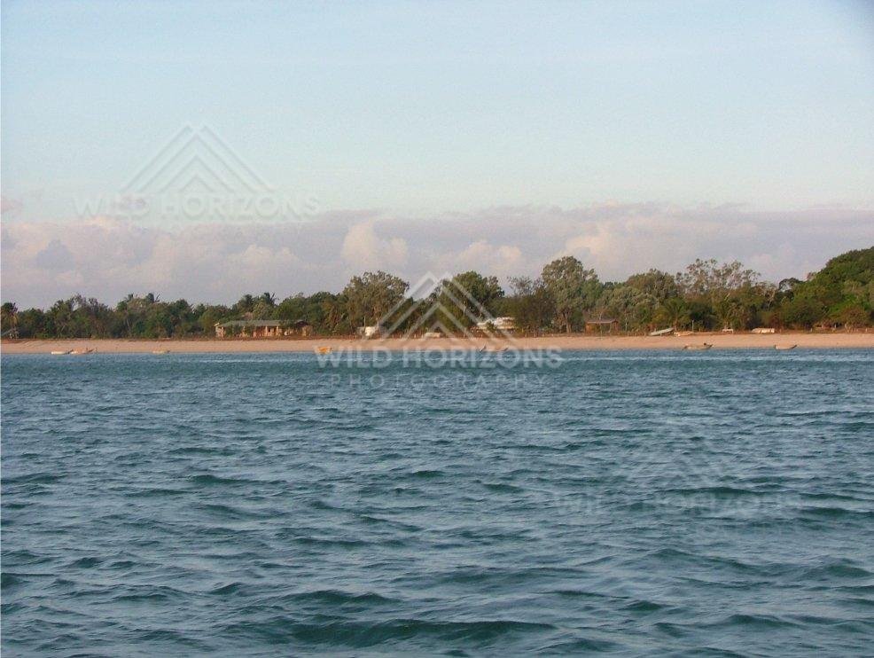 Sandy shoreline and coastal settlement viewed from offshore. Seisia, Australia.