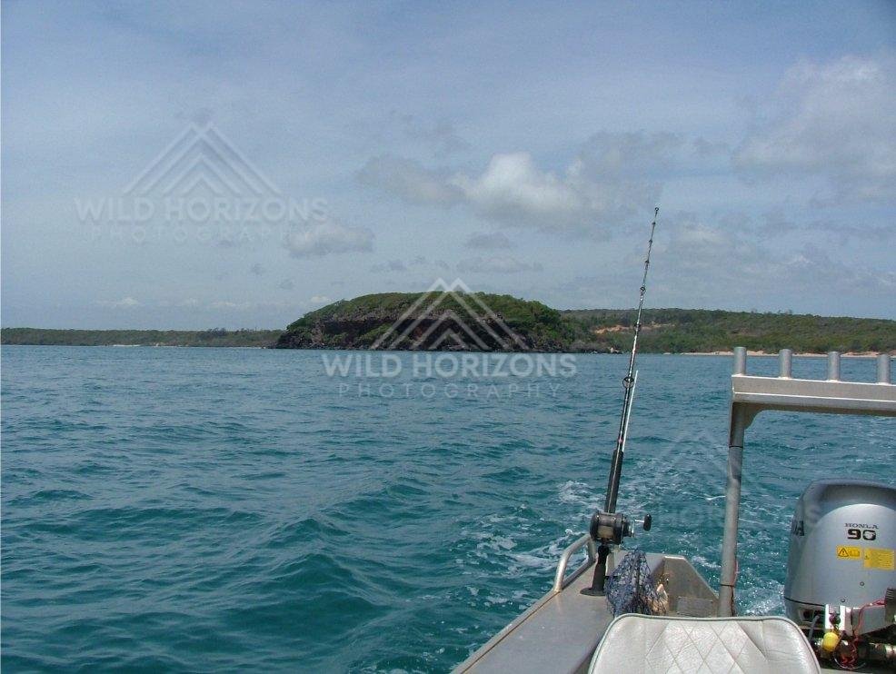 Fishing from a small boat near wooded coastline. Seisia, Australia.