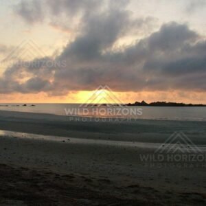 Sunset over calm ocean with dramatic storm clouds and distant rocky islets. Cape York, Australia.