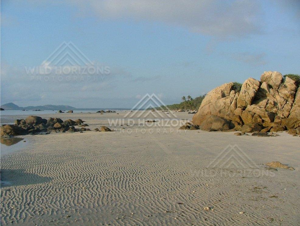 Granite boulders on the shoreline with offshore islands beyond. Chili Beach, Australia.