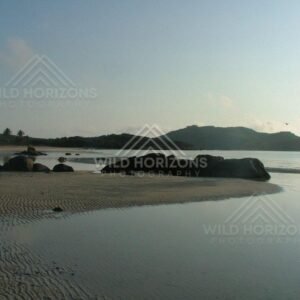 Rippled sand flats with granite boulders beside a quiet bay. Chili Beach, Australia.