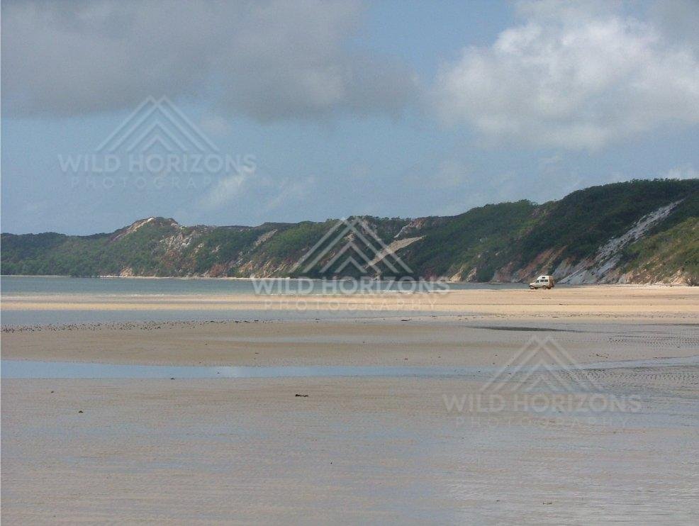 On a bright afternoon at Elim Beach, calm shallow waters reflect distant cliffs and open skies. Elim Beach, Australia.