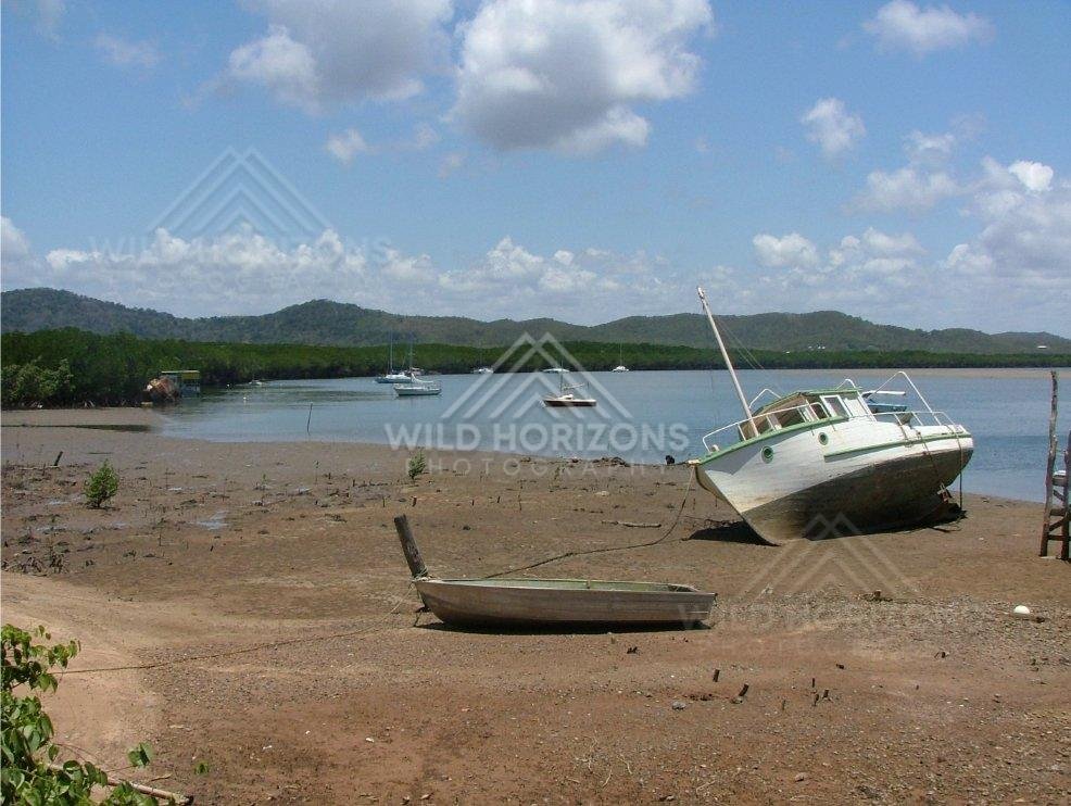 At Cooktown harbour, beached fishing boats sit on exposed mud flats as the tide falls. Cooktown, Australia.