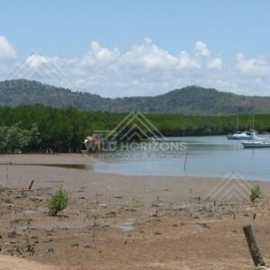 Across Cooktown, mangrove-lined inlets and moored yachts are viewed over broad tidal flats. Cooktown, Australia.