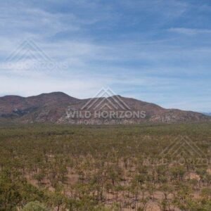 Across the Cape York Area, rugged hills rise above sparse bushland beneath wide blue skies. Cape York Area, Australia.