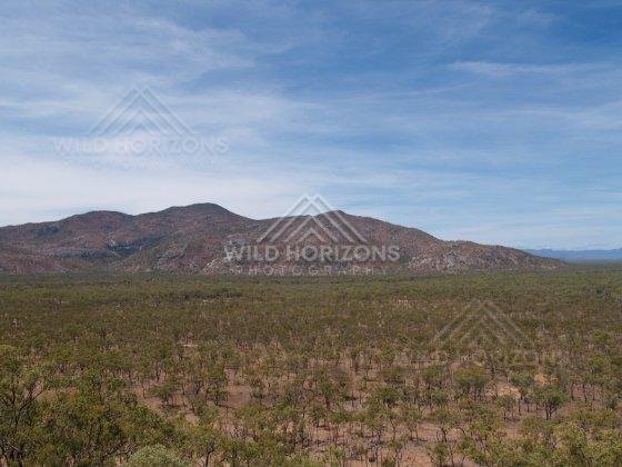 Across the Cape York Area, rugged hills rise above sparse bushland beneath wide blue skies. Cape York Area, Australia.