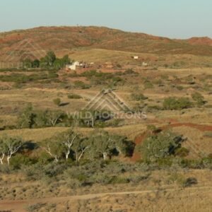 Isolated outback homestead set against red rocky hills and open grass plains. Pilbara, Australia.