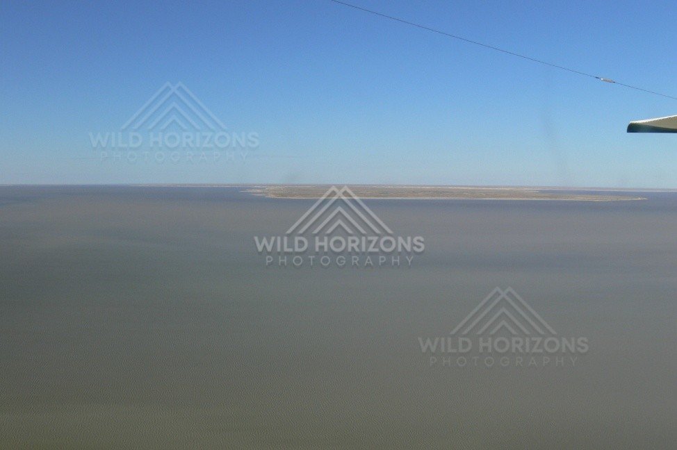 Isolated sand island within inland lake waters. Lake Eyre Basin, Australia.