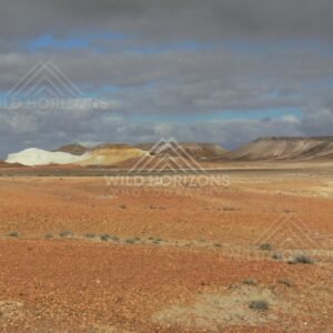 Wide view of cream and ochre Breakaways ridges beneath dramatic desert cloud. Kanku-Breakaways Conservation Park/Coober Pedy, Australia.
