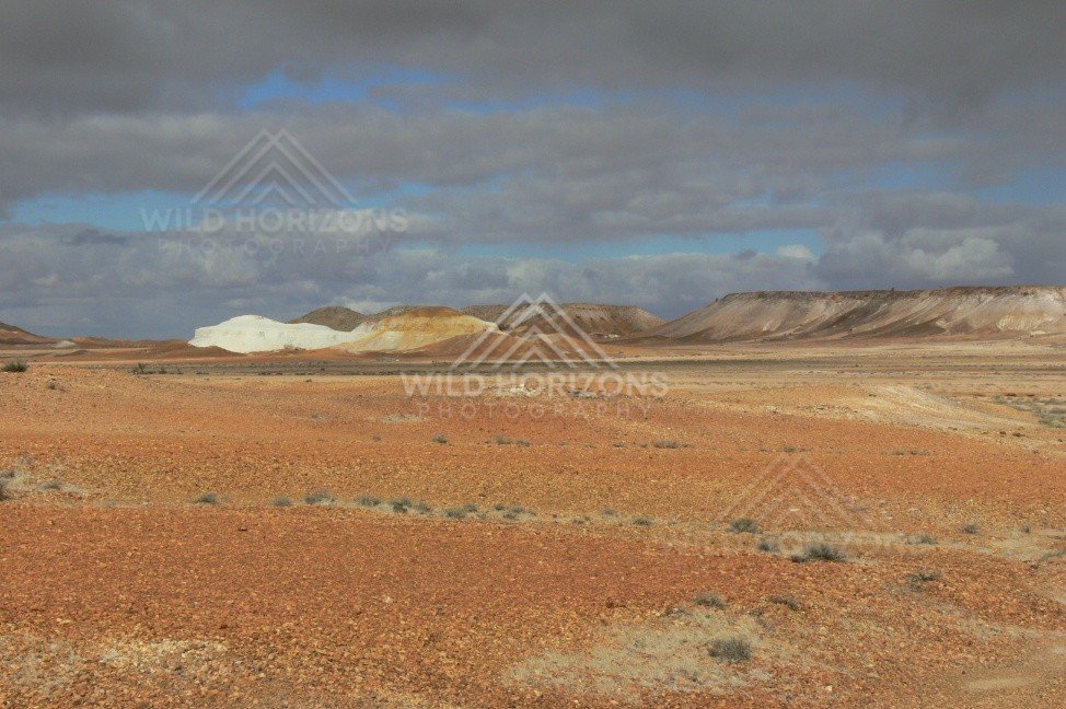 Wide view of cream and ochre Breakaways ridges beneath dramatic desert cloud. Kanku-Breakaways Conservation Park/Coober Pedy, Australia.