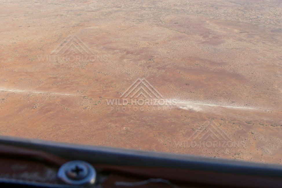 Vehicle crossing remote Channel Country track raising dust. Cooper Creek Region, Australia.