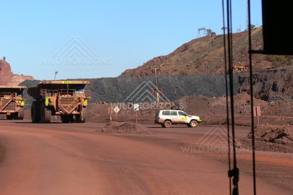 Haul truck passing a mine utility vehicle on a red dirt access road. Pilbara, Australia.