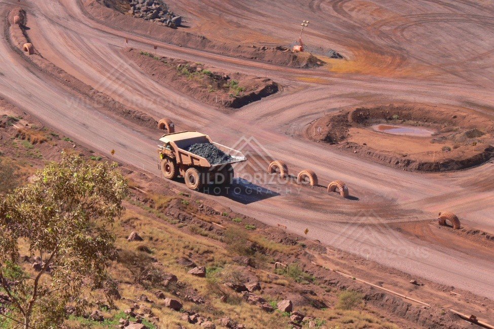 Loaded haul truck descending switchback ramps within an open-cut iron-ore pit. Pilbara, Australia.