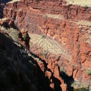 Sunlit ironstone escarpment above a Karijini gorge pool. Pilbara, Australia.