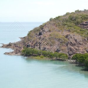 Rocky island headland rising from blue sea. Cape York, Queensland, Australia.
