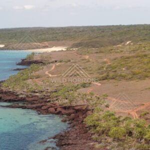 Aerial view of red rocky Cape York shoreline and turquoise shallows. Narau Beach, Queensland, Australia.