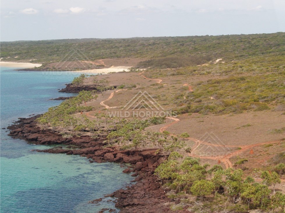 Aerial view of red rocky Cape York shoreline and turquoise shallows. Narau Beach, Queensland, Australia.