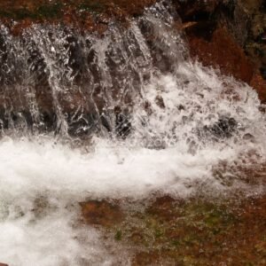 Small waterfall cascading over red sandstone into a clear pool. Fruitbat Falls, Queensland, Australia.