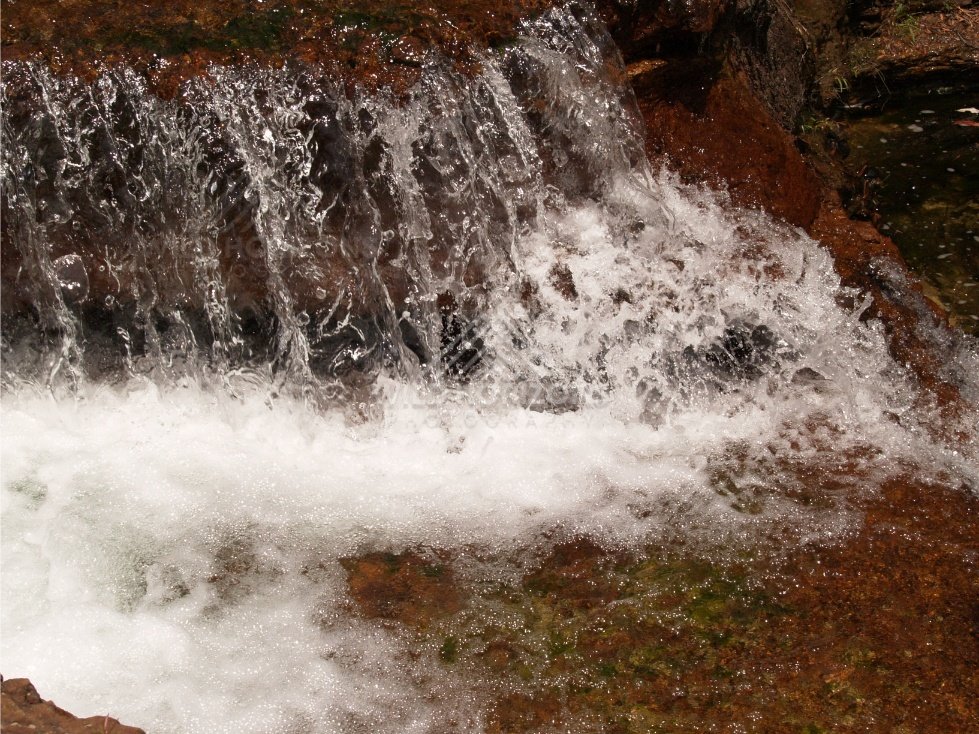 Small waterfall cascading over red sandstone into a clear pool. Fruitbat Falls, Queensland, Australia.
