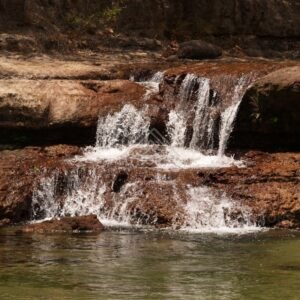 Multi-tiered waterfall across layered red rock. Fruitbat Falls, Queensland, Australia.