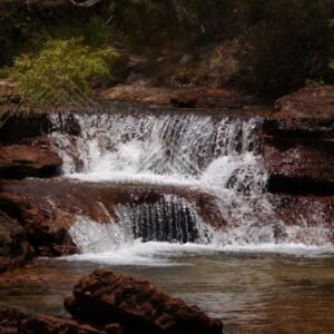 Broad step waterfall dropping into shaded pool. Fruitbat Falls, Queensland, Australia.