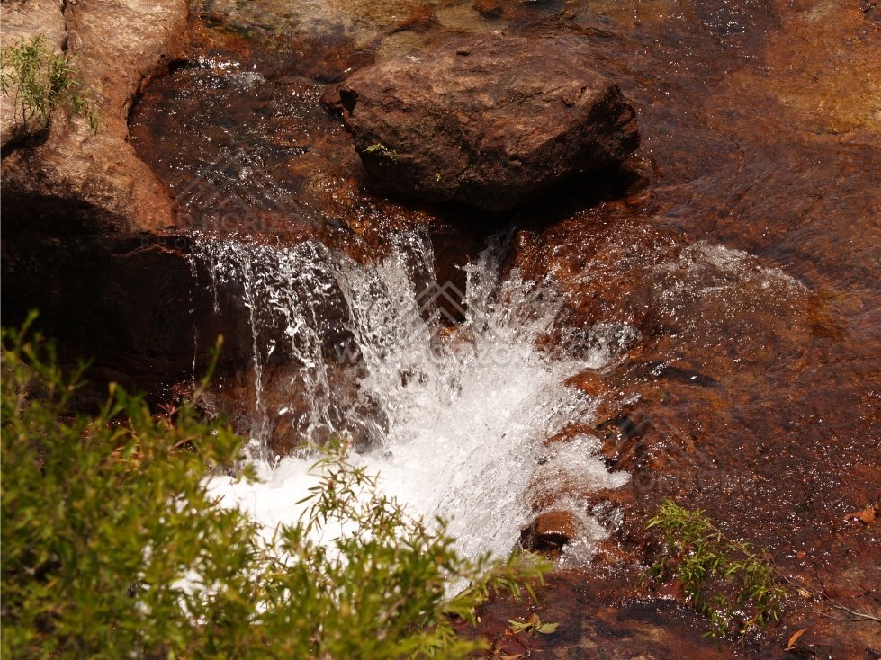 Water pouring over dark rock lip. Fruitbat Falls, Queensland, Australia.