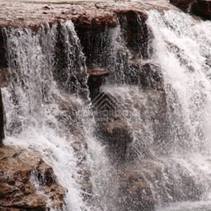 Water pouring over layered rock face. Fruitbat Falls, Queensland, Australia.