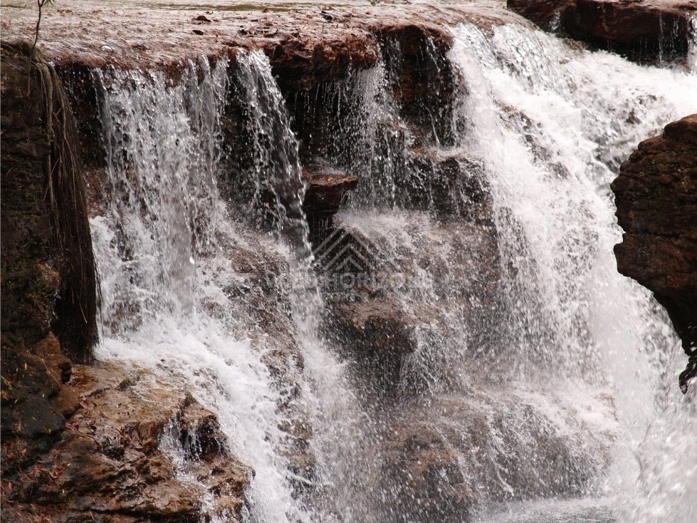 Water pouring over layered rock face. Fruitbat Falls, Queensland, Australia.