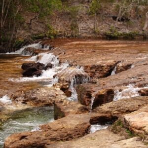 Shallow cascades across red stone platform. Fruitbat Falls, Queensland, Australia.