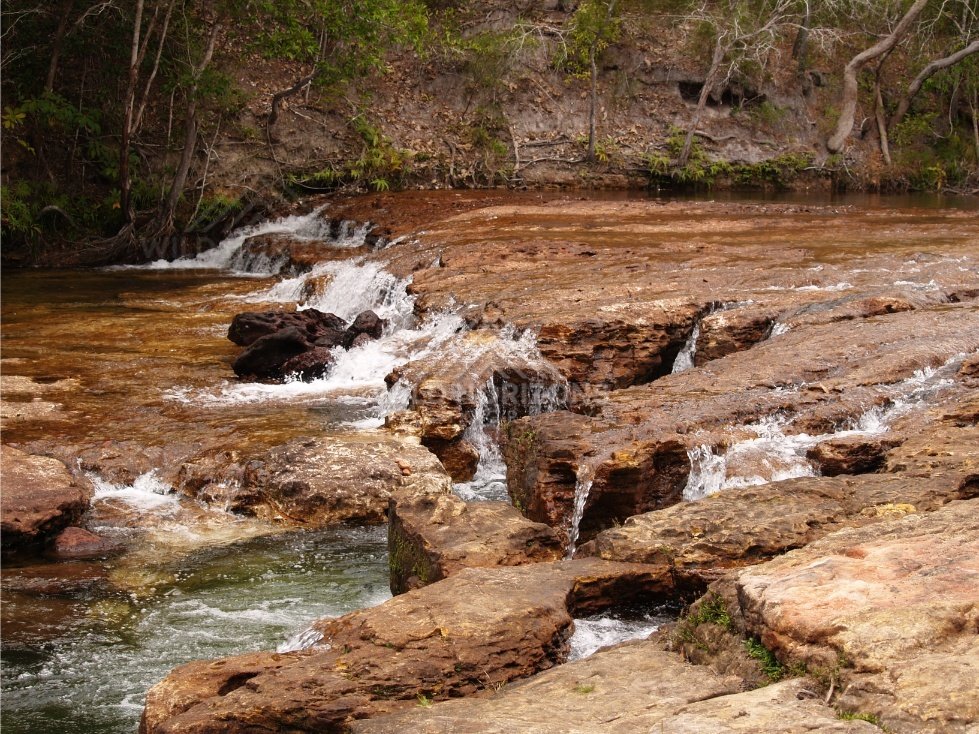 Shallow cascades across red stone platform. Fruitbat Falls, Queensland, Australia.